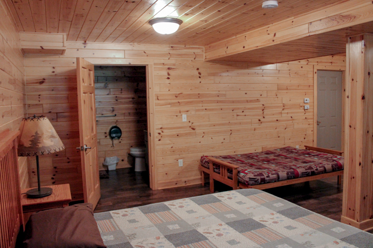 Second view of lower level basement showing door to bathroom from queen-sized bed.