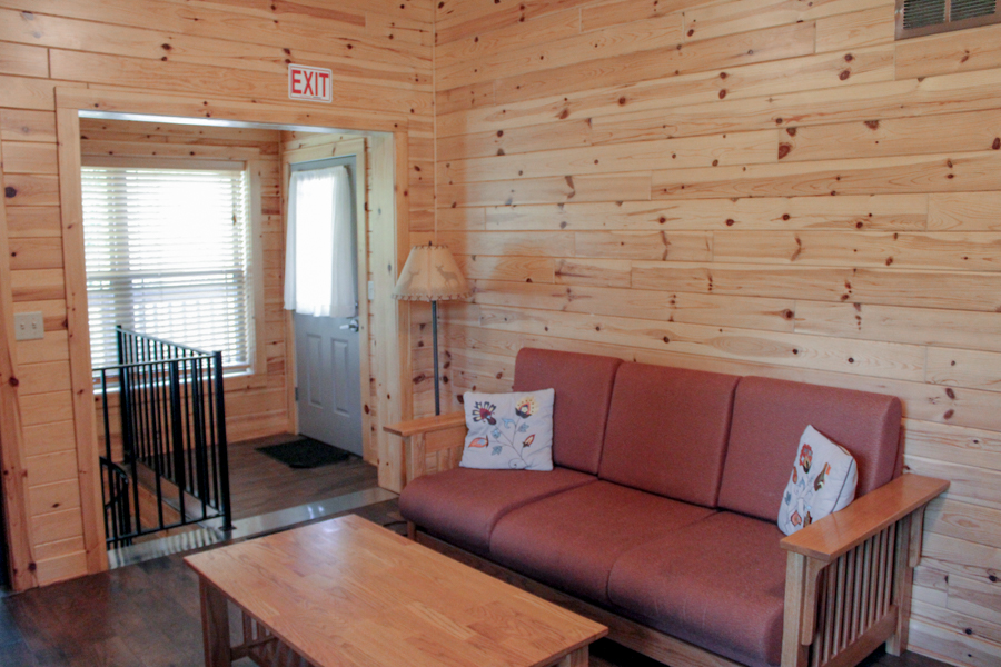 Cabin 4 living room futon and coffee table, with door to back deck beyond.