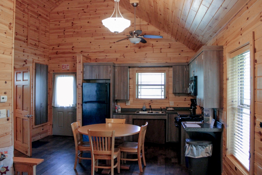 Cabin 2 Kitchen overview from living room including kitchen sink, refrigerator, table, and front doo