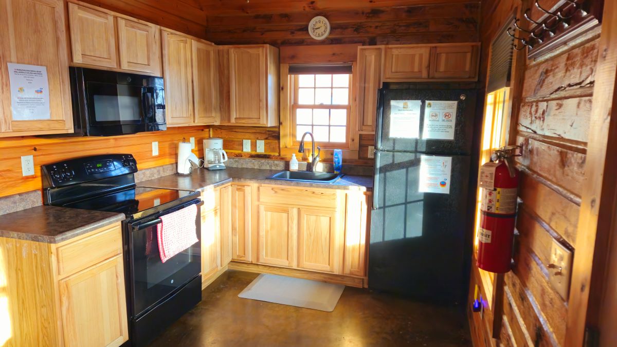 Oak Cabin kitchen with microwave, refrigerator, stove and cabinets with plates, cups, silverware, ut