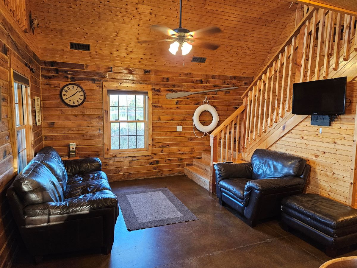 Lakeview cabin livingroom with sofa, chair and ottoman. Steps on the right going upstairs