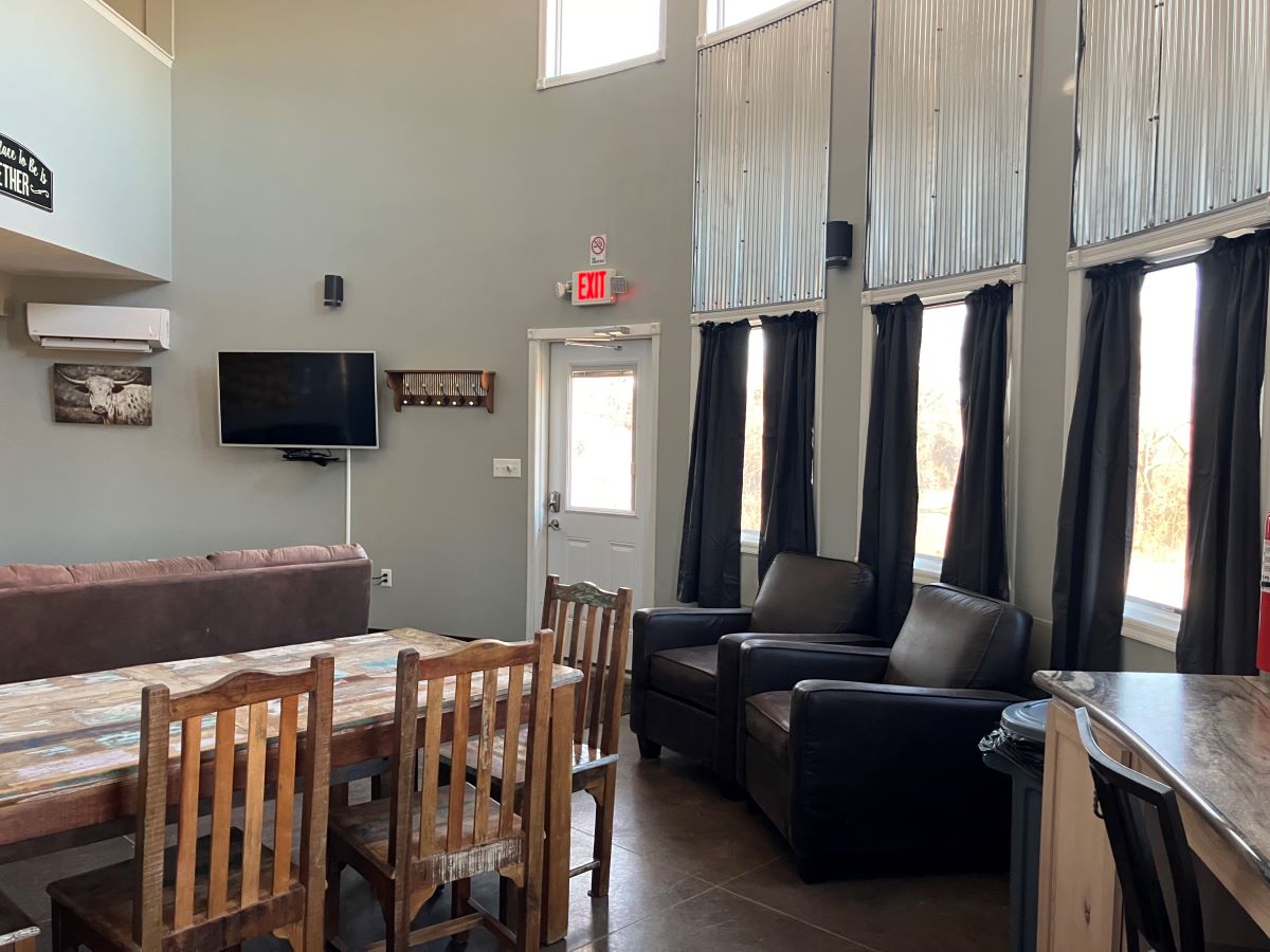 Grain Bin Cabin main floor view from the kitchen to the exterior door with kitchen table and two arm