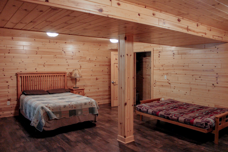 Cabin 3 walk-out basement area showing laid out double fouton and queen sized bed, as well as door t