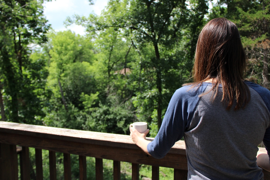 Woman enjoying looking out of the cabin patio with a cup of coffee