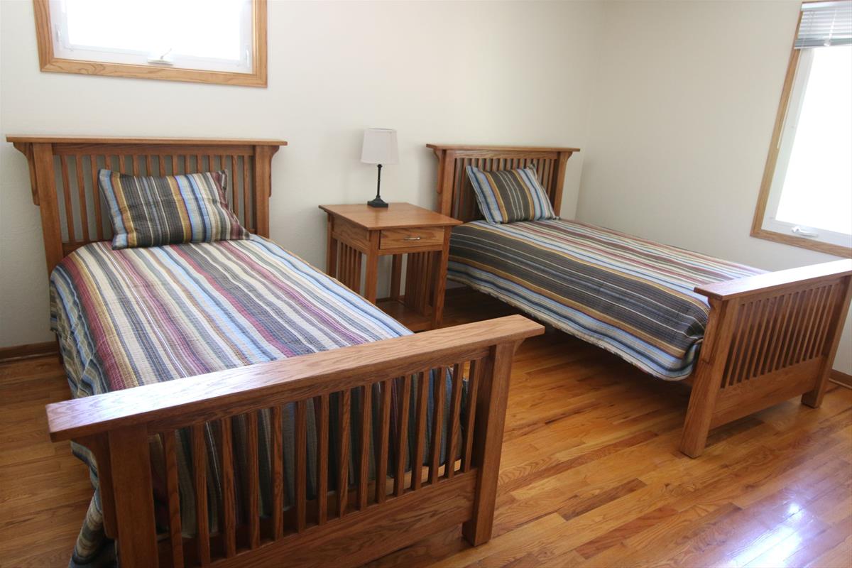 Second cabin bedroom including two twin beds on wood mission bedframes, and shared nightstand. 