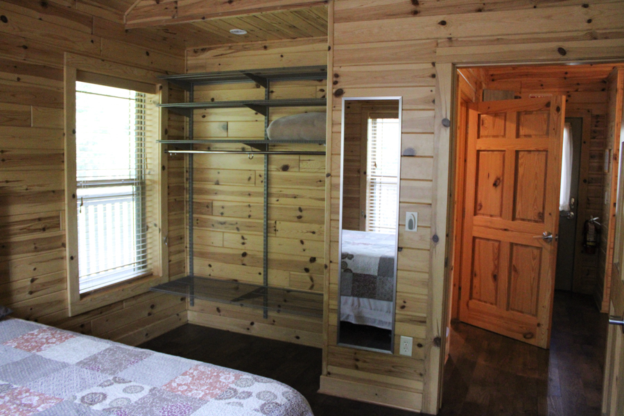 Cabin 2 bedroom shelving looking out of the room onto the bathroom door off the kitchen