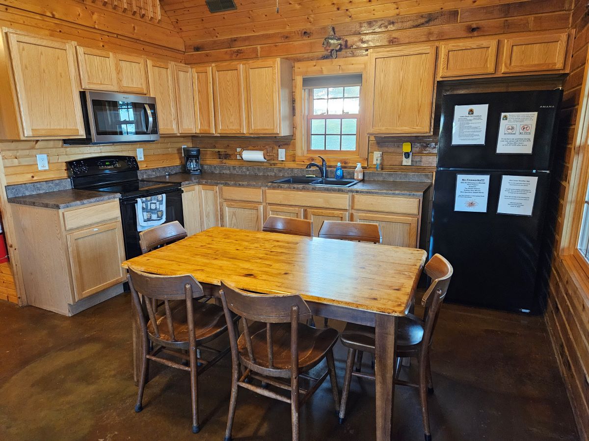 Lakeview cabin kitchen. Includes microwave, stove, coffee pot, table and chairs, refrigerator. Cabin