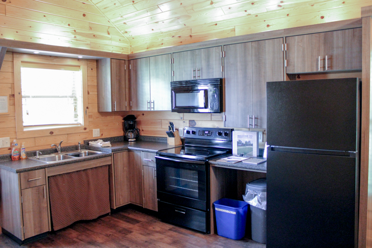 Cabin 3 kitchen including stove, mounted microwave, sink, and refrigerator