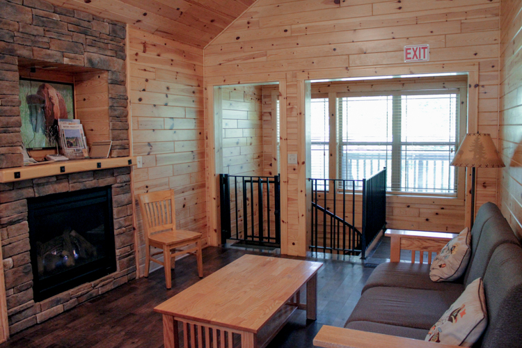 Cabin 3 view of living room including fireplace, coffee table, futon, and door to back deck