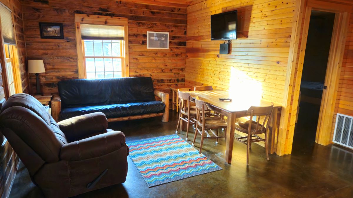 Oak Cabin - living room with recliner, sofa that is a full-size bed and table with chairs