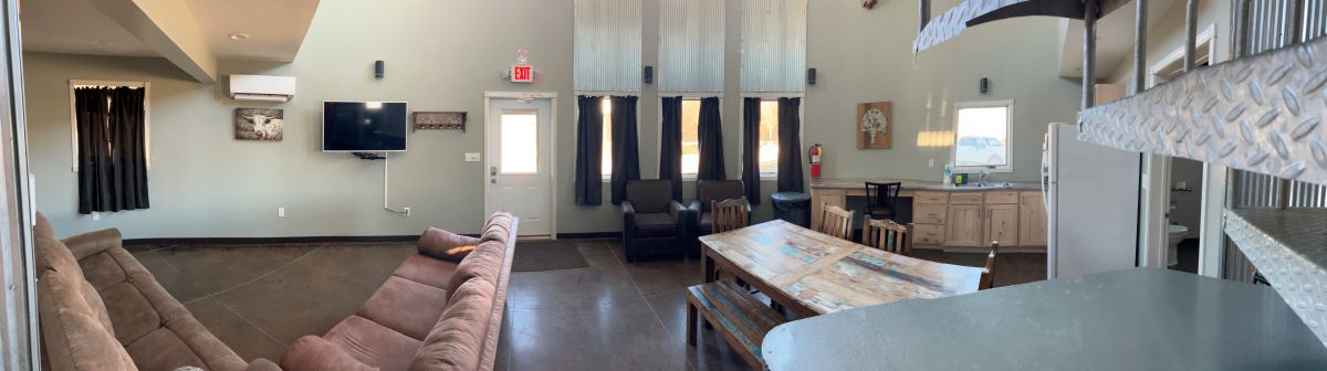 Grain Bin Cabin main floor view featuring two couches, two arm chairs and a kitchen table